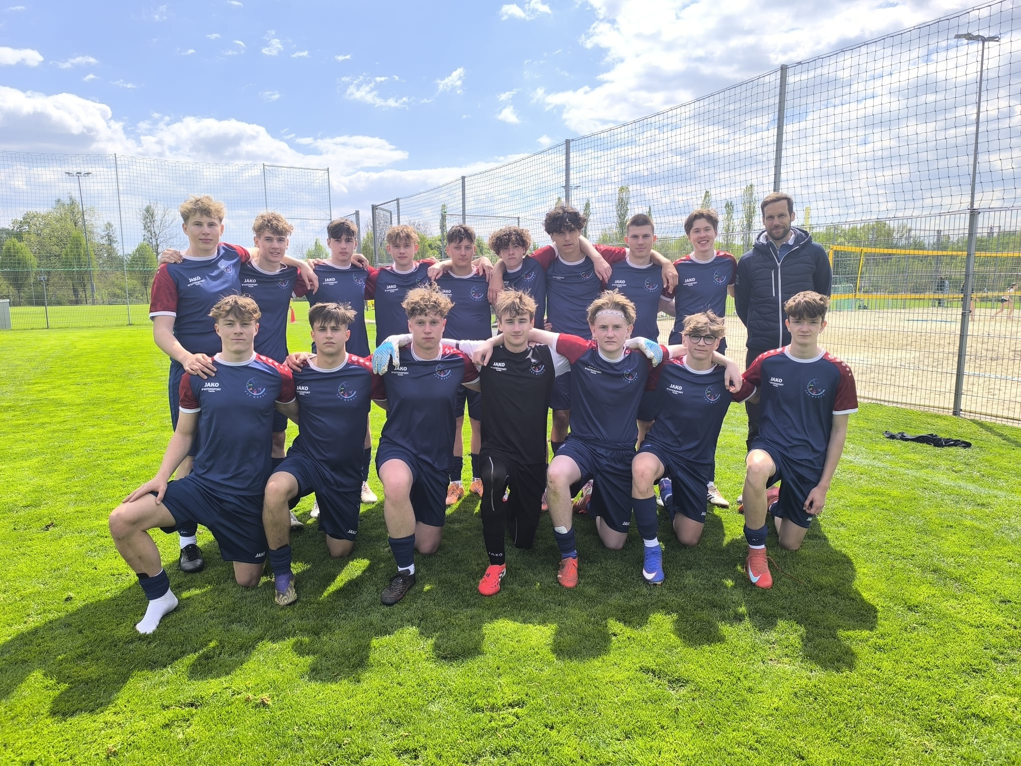 Fußballteam mit Trainer auf einem Rasenplatz